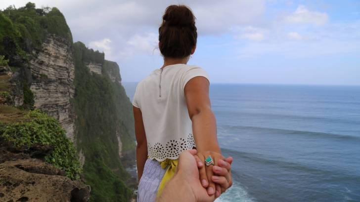couple on the cliff overlooking the ocean, holding hands