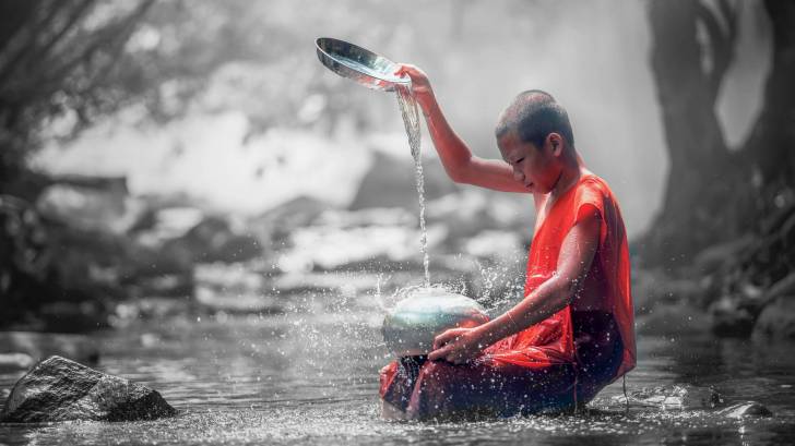 monk getting clean water out of a stream