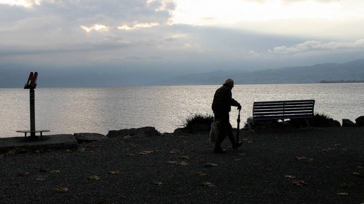 dawn is rising, man walking with a cane near the sound