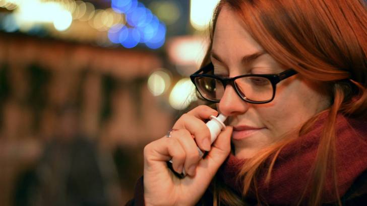 woman taking a nasal spary for the flu
