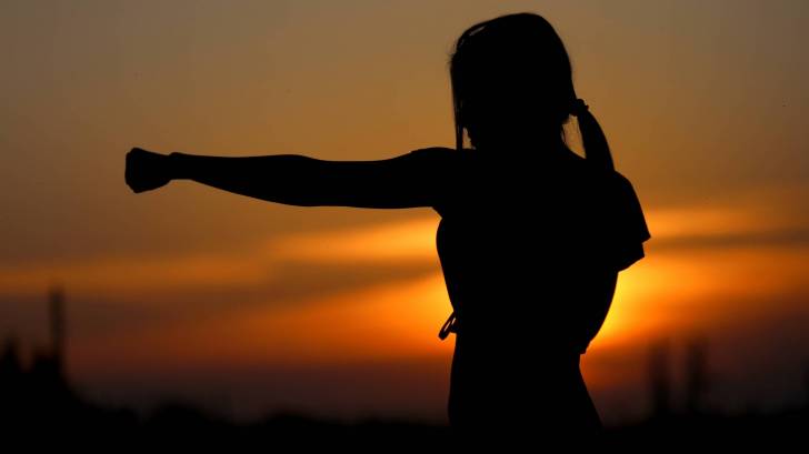 karate female at sunset punching the cancer