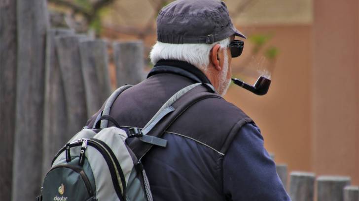 older man puffing on pipe taking a walk