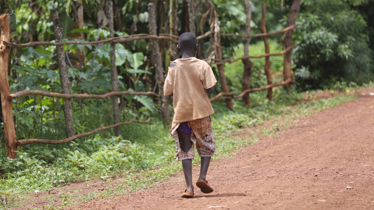 african boy walking down the dirt road