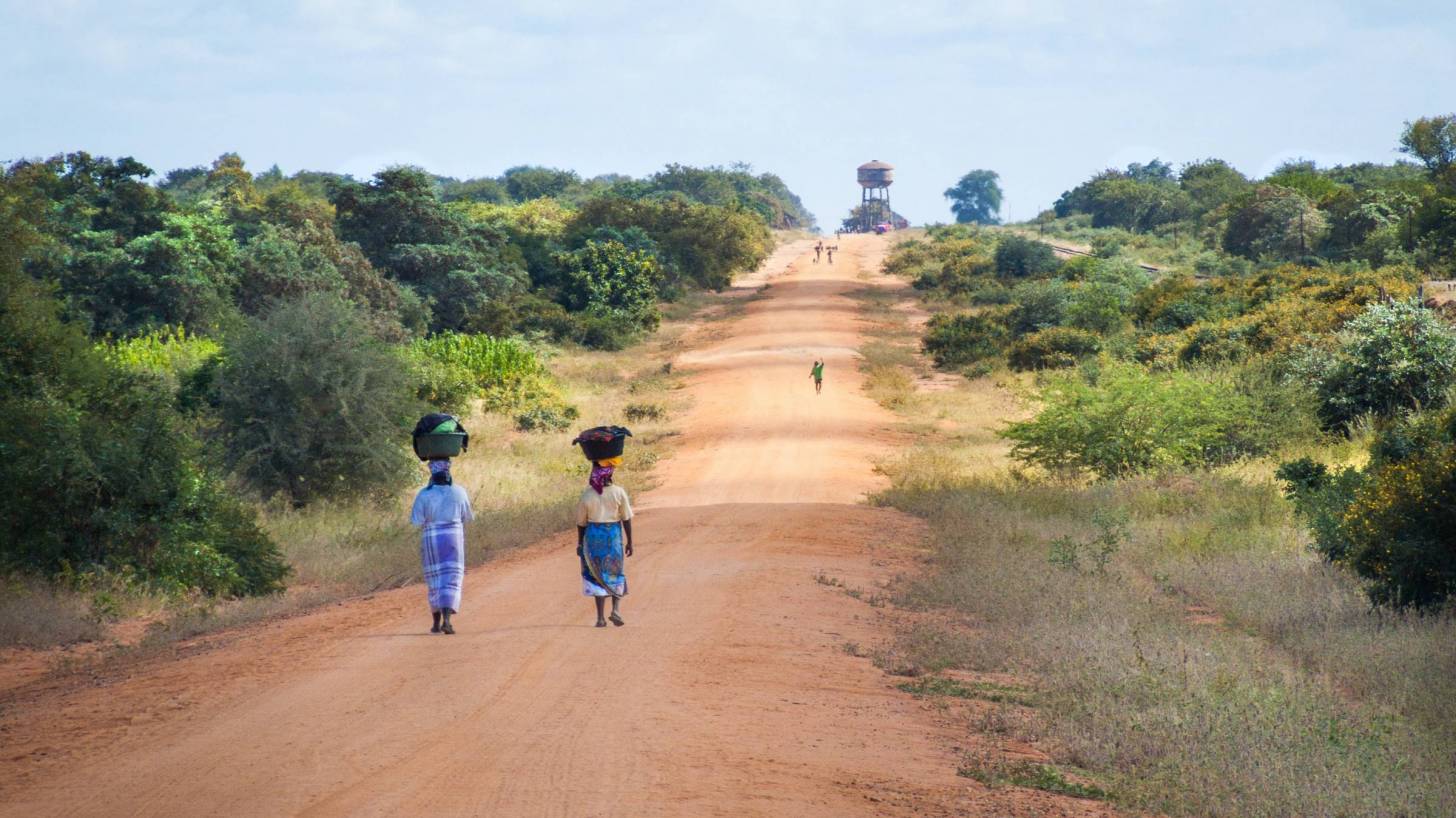 african women walking to get water on dusty road