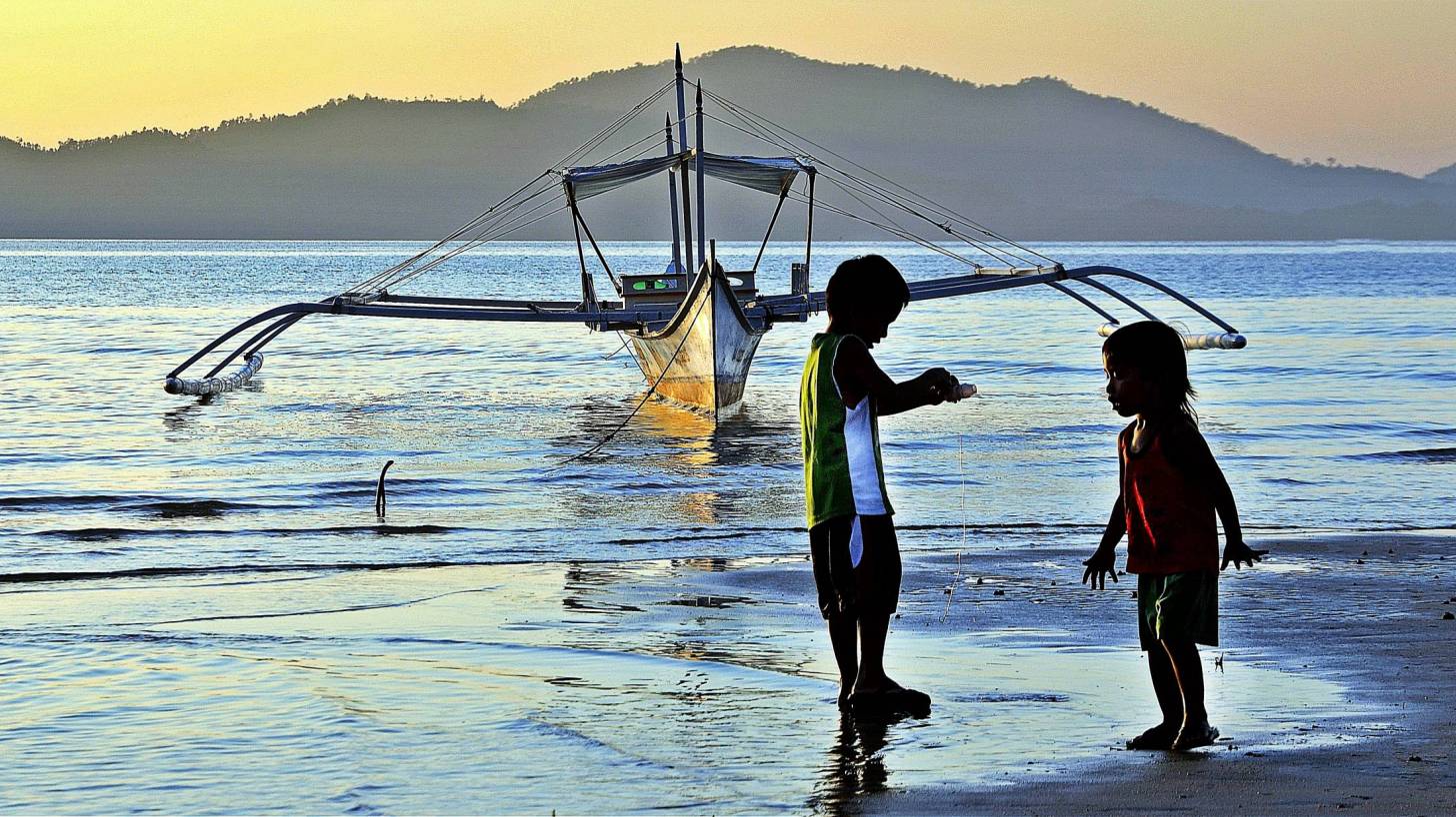 filipino children playing on the beach fishing