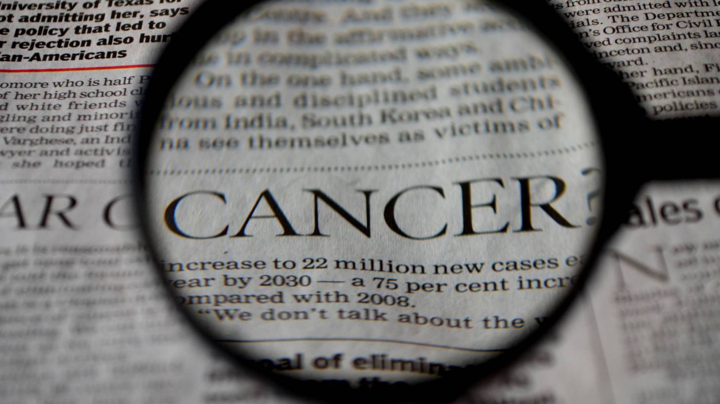 cancer word under a magnifying glass in a news paper