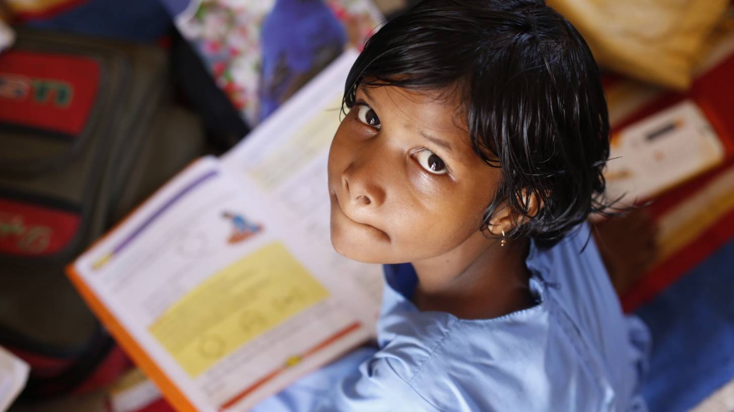 young indian girl studying, looking up at the camera