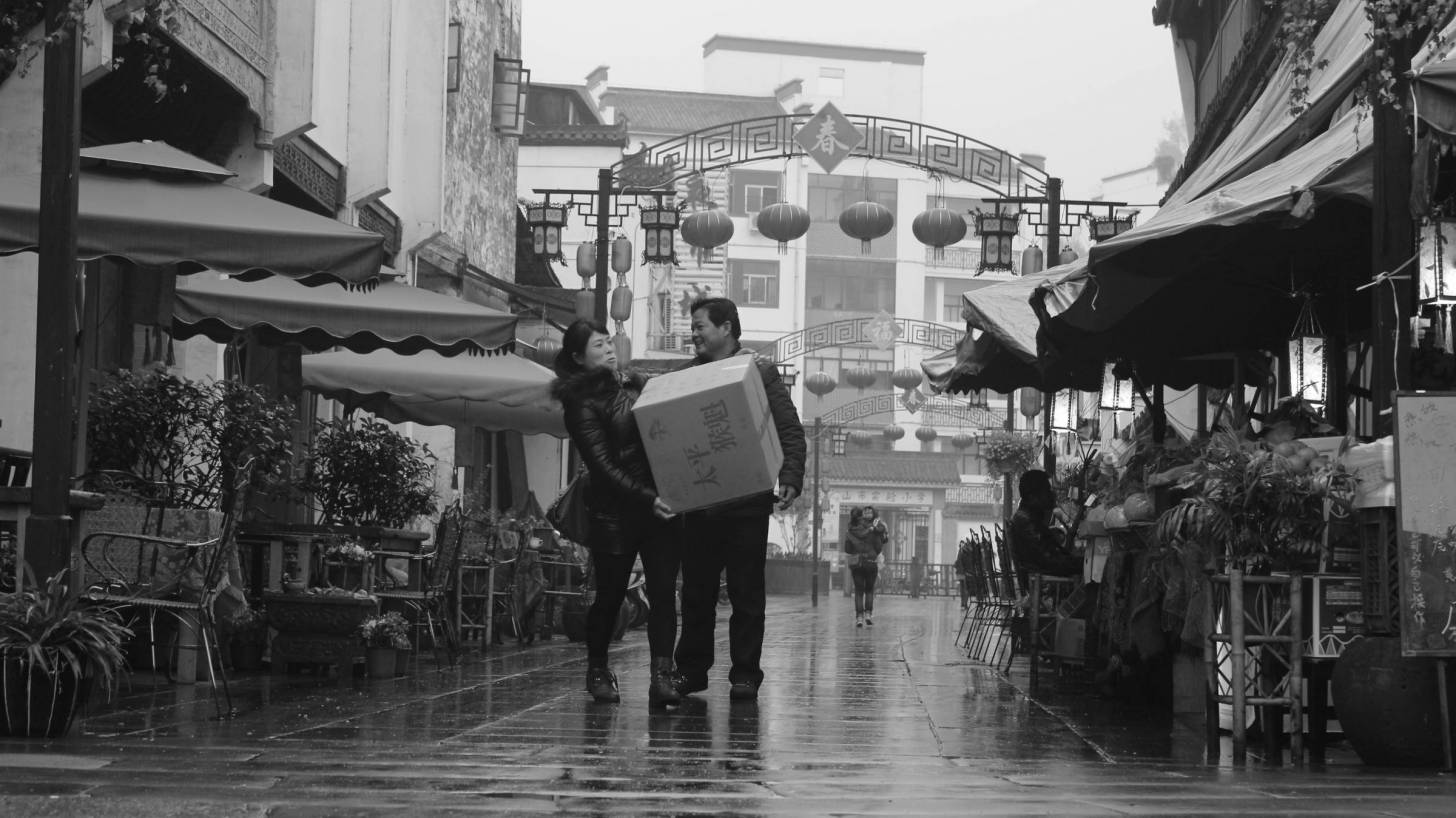 chinese couple carrying a heavy box