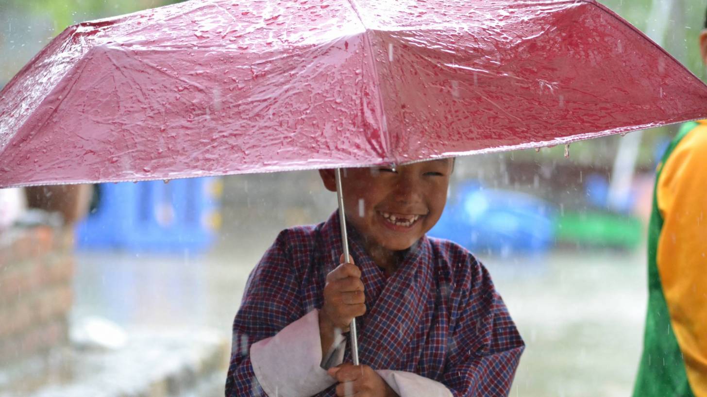 cute little boy holding umbrella in the rain