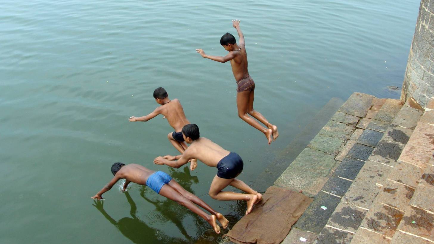 boys diving into river in India, hot weather