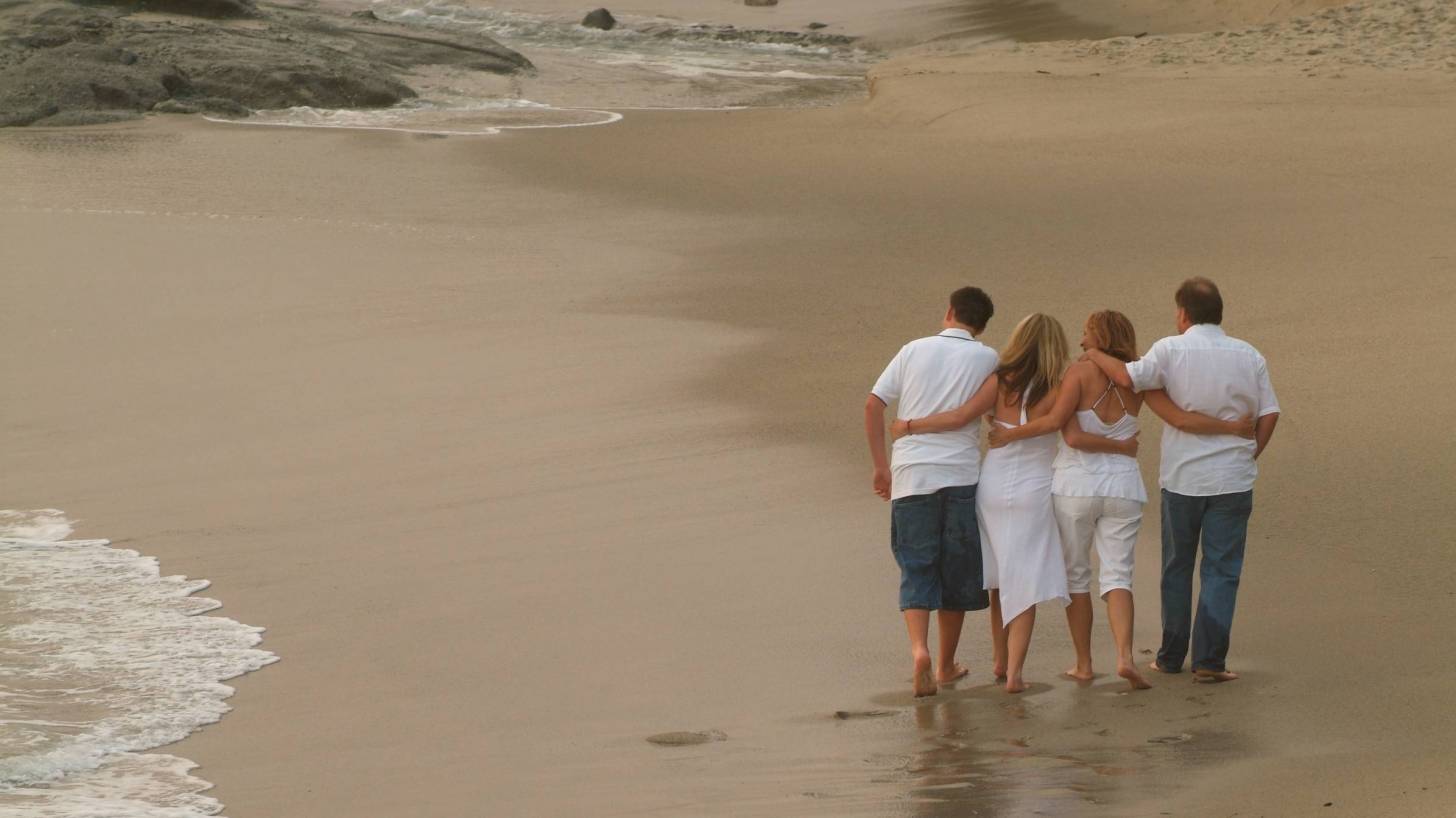 family of adults walking on a beach
