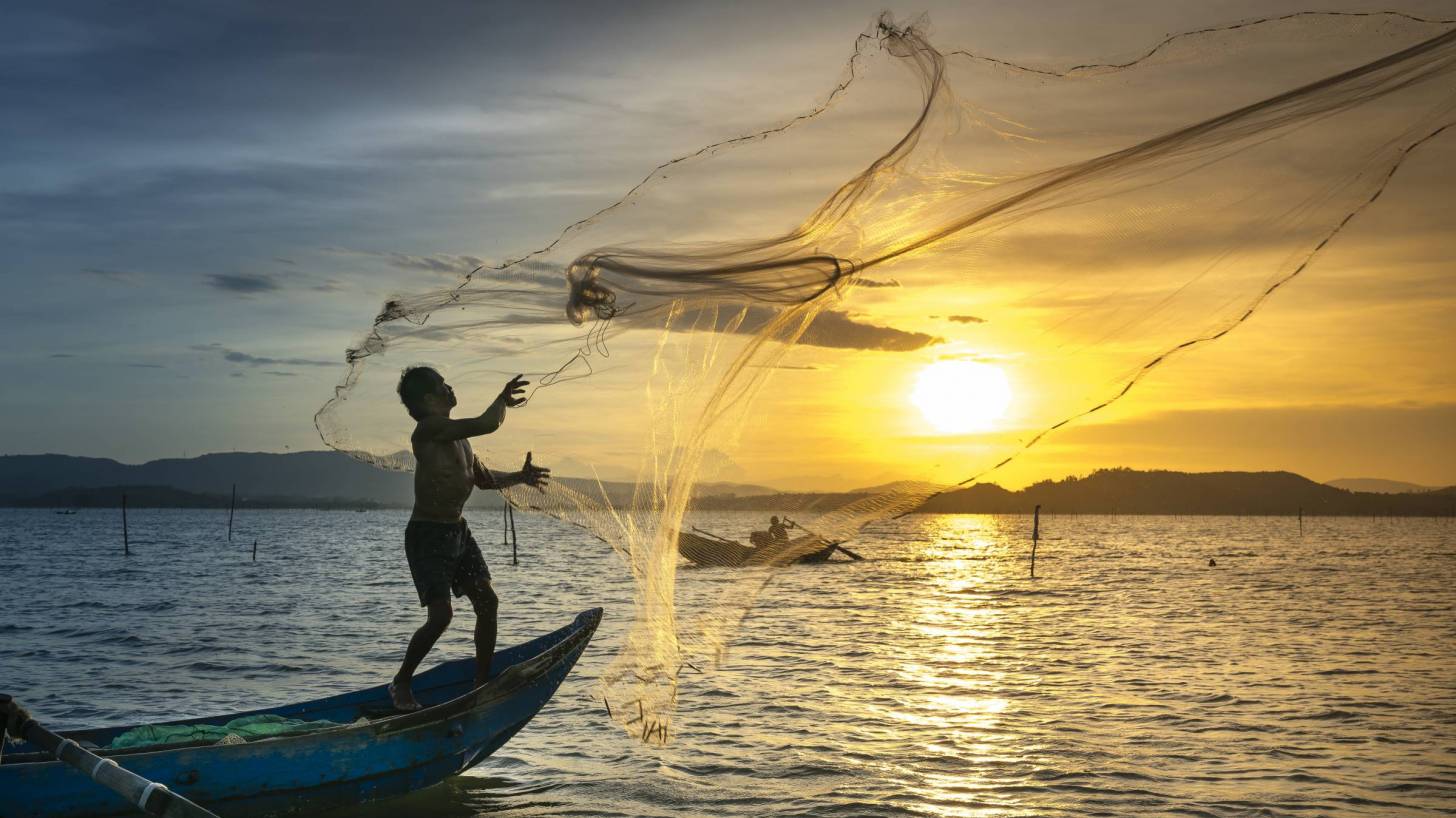 Fishermen casting nets in the sunset