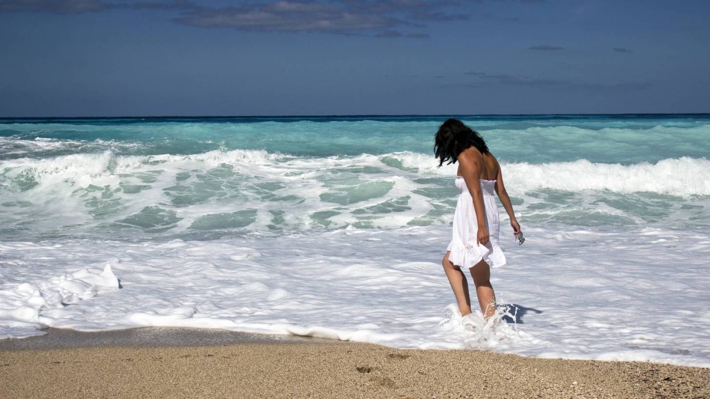 young woman walking on a sandy beach in the surf