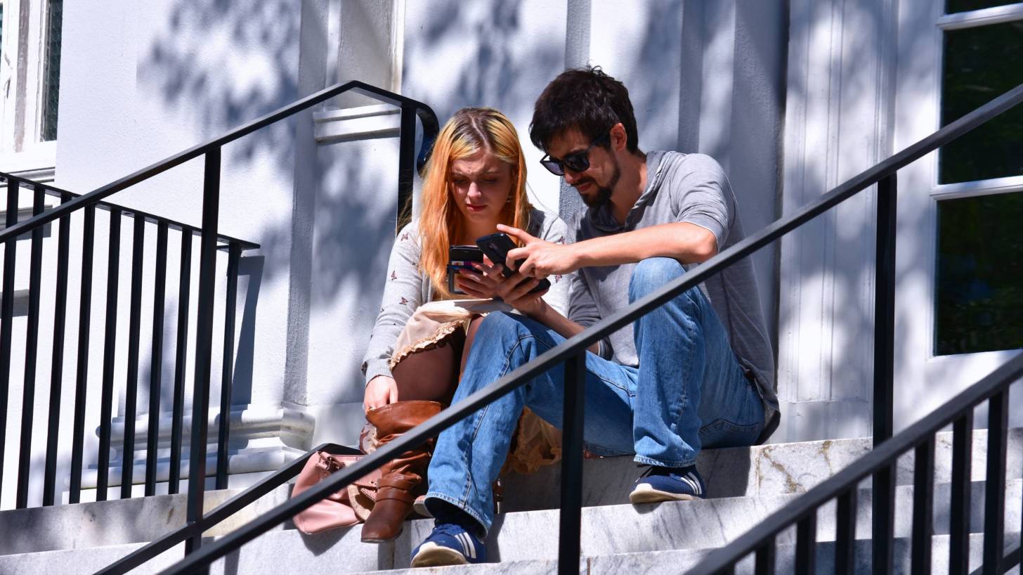 couple sitting on the steps of a CofC building