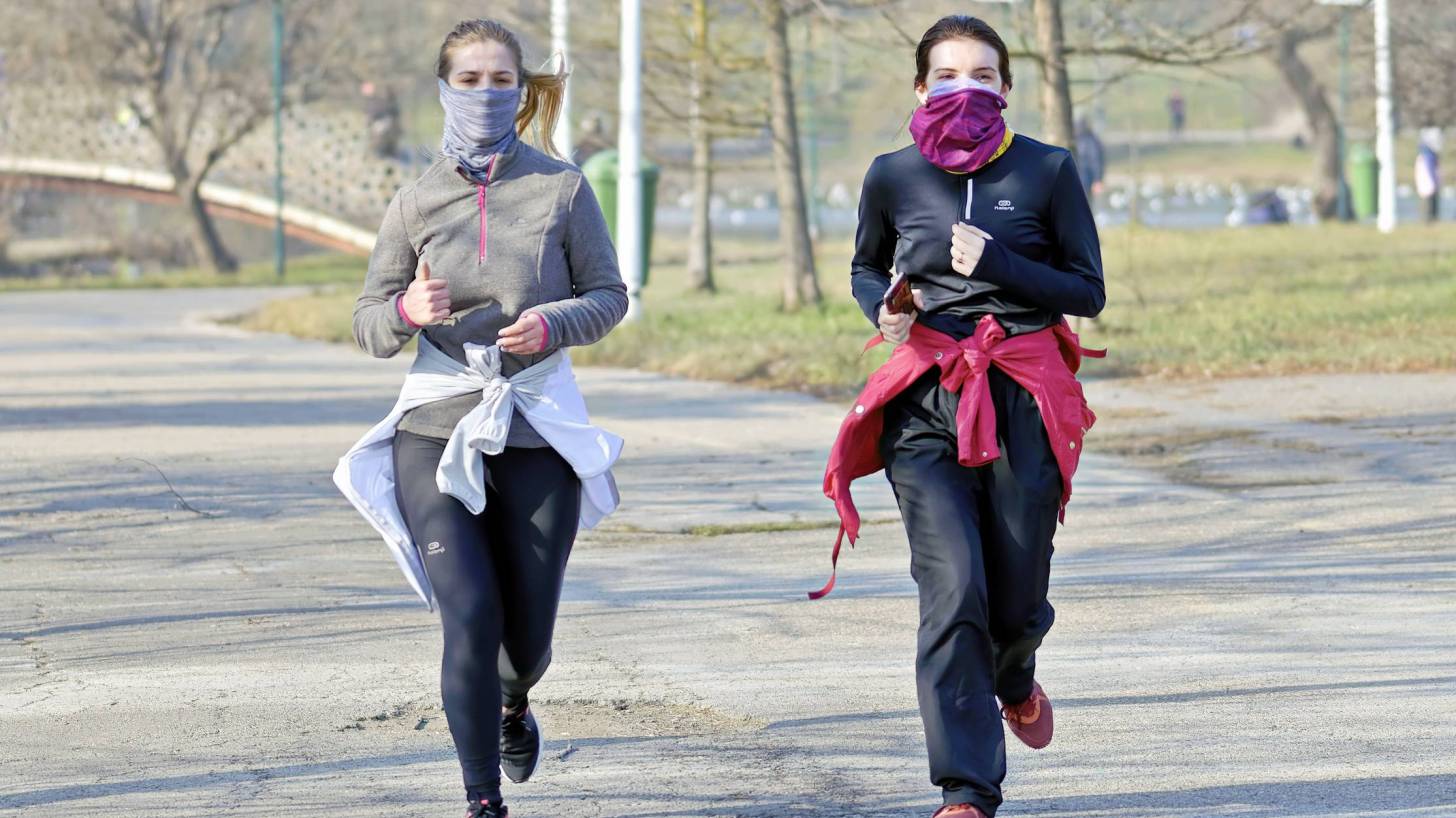 women running in a park, with masks and separate, no others around them
