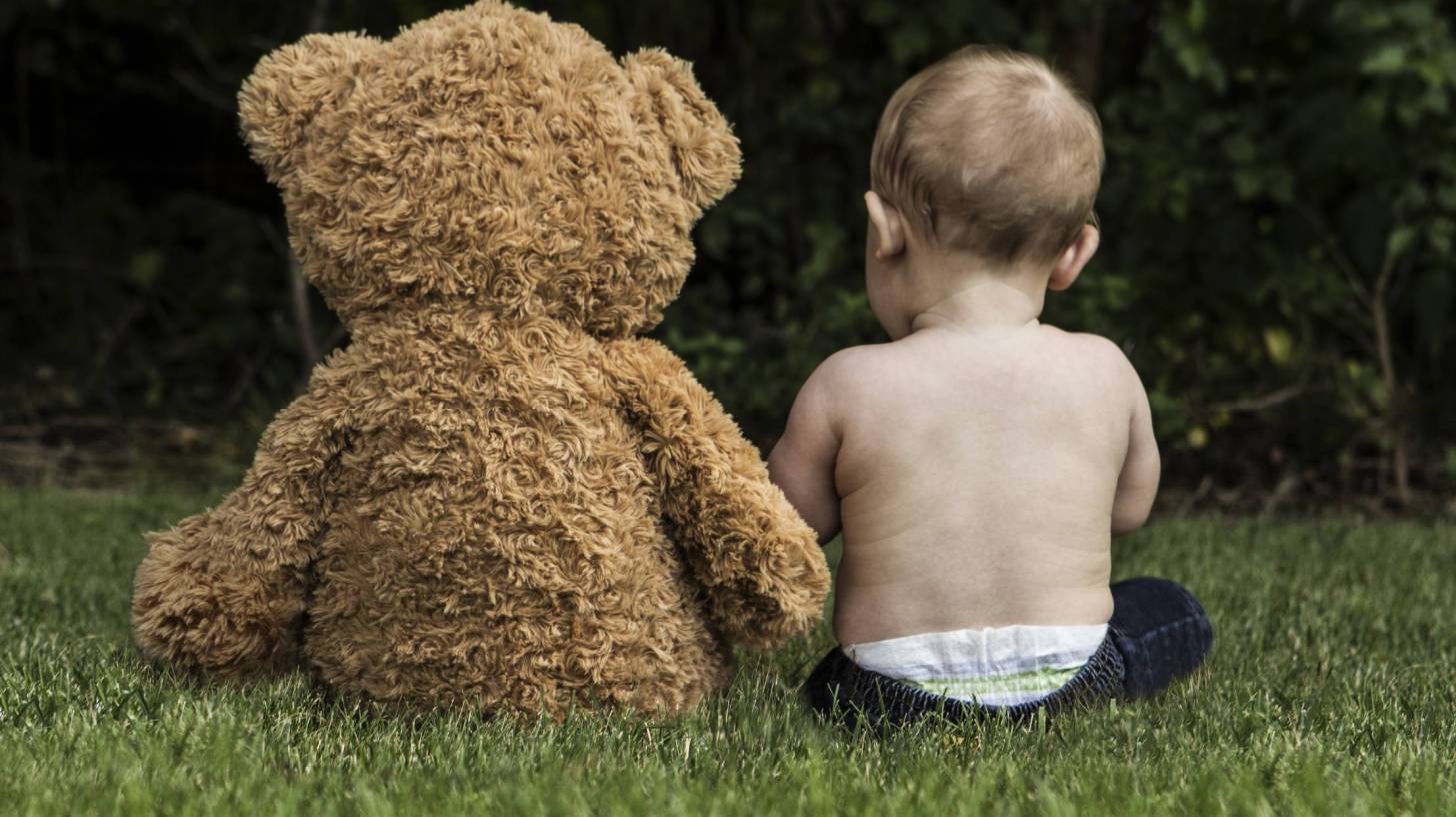 toddler sitting on ground with Teddy bear