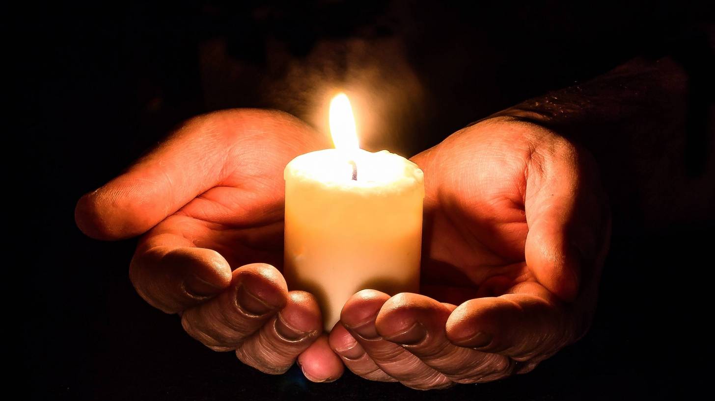 hands holding a candle in pray
