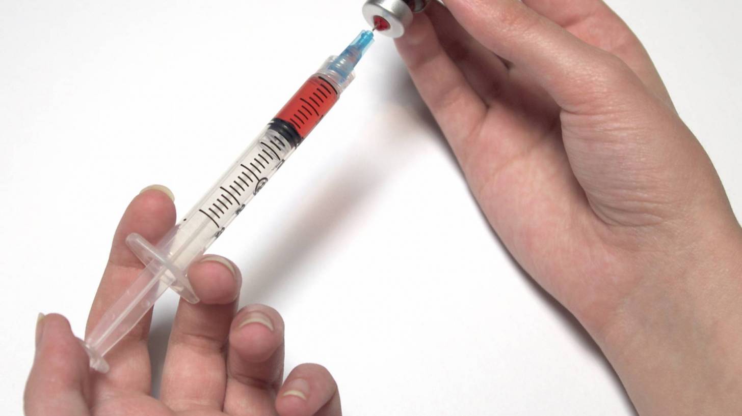 pharmacist loading up a syringe with a flu shot