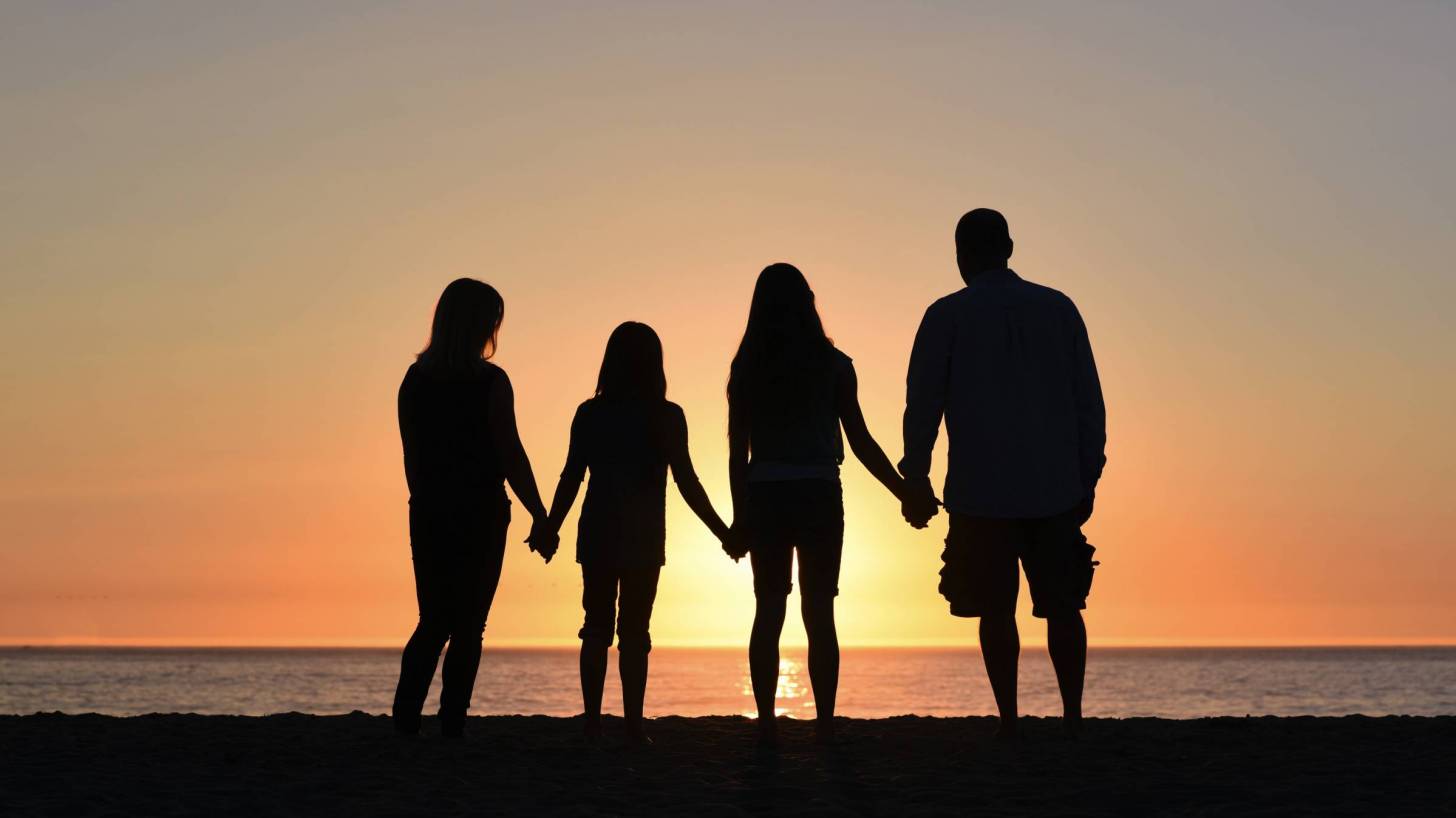family on beach at sunset holding hands