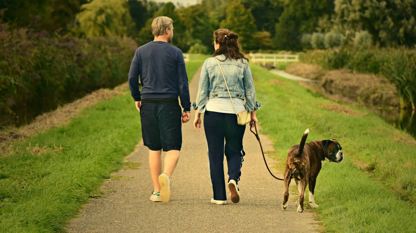 couple walking on a road with dog, healthy and happy