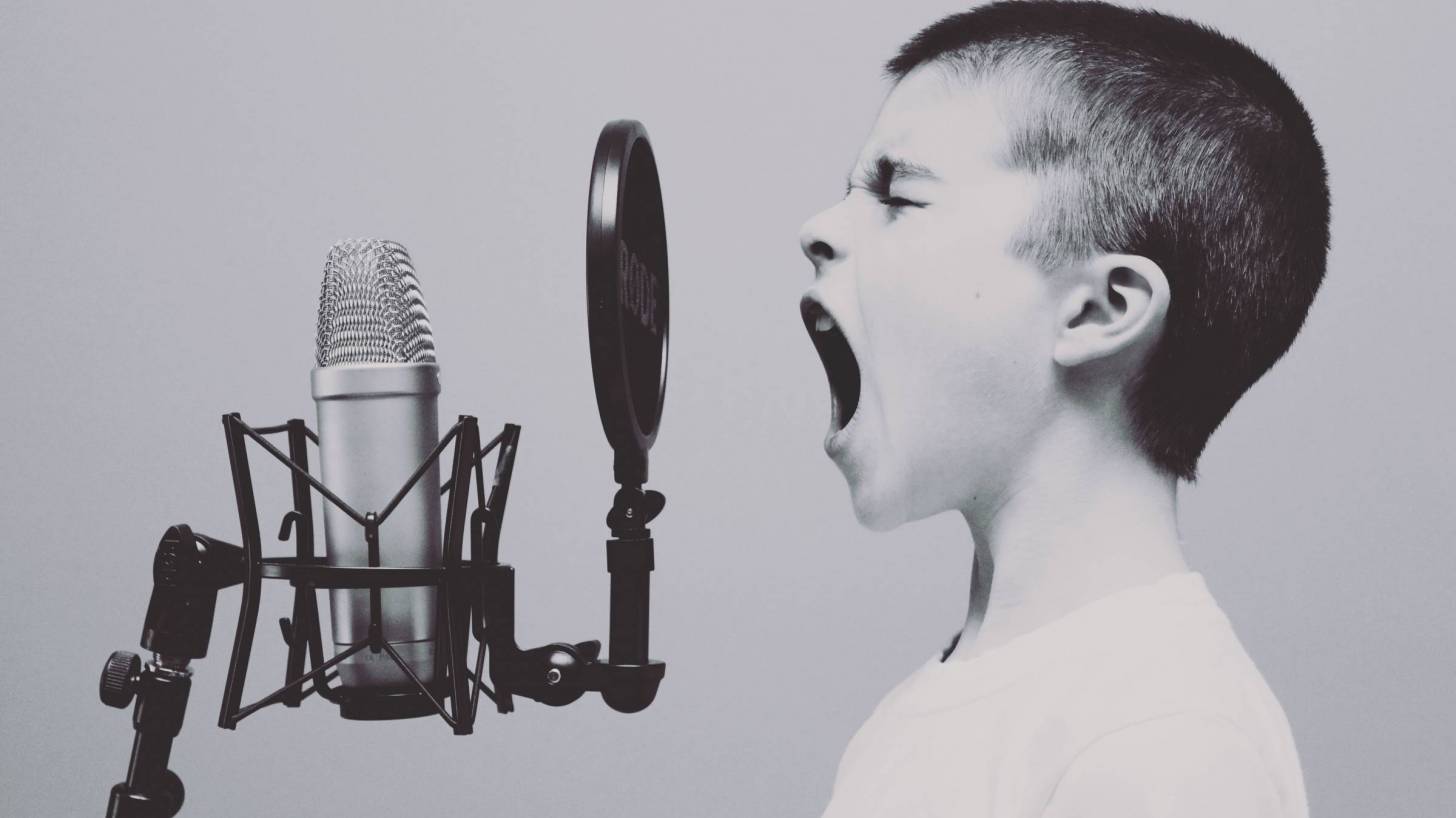 young boy yelling into an old fashion microphone