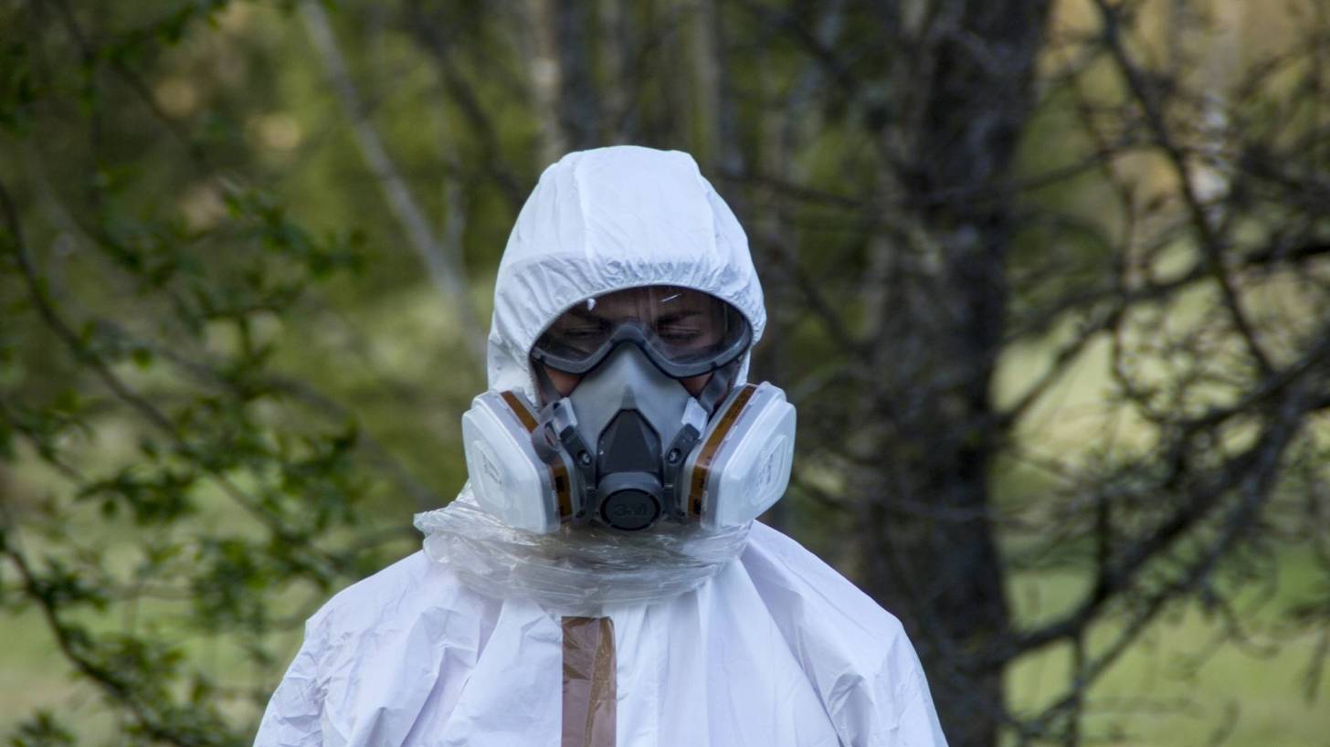 Man in bio hazard wuit and gas mask