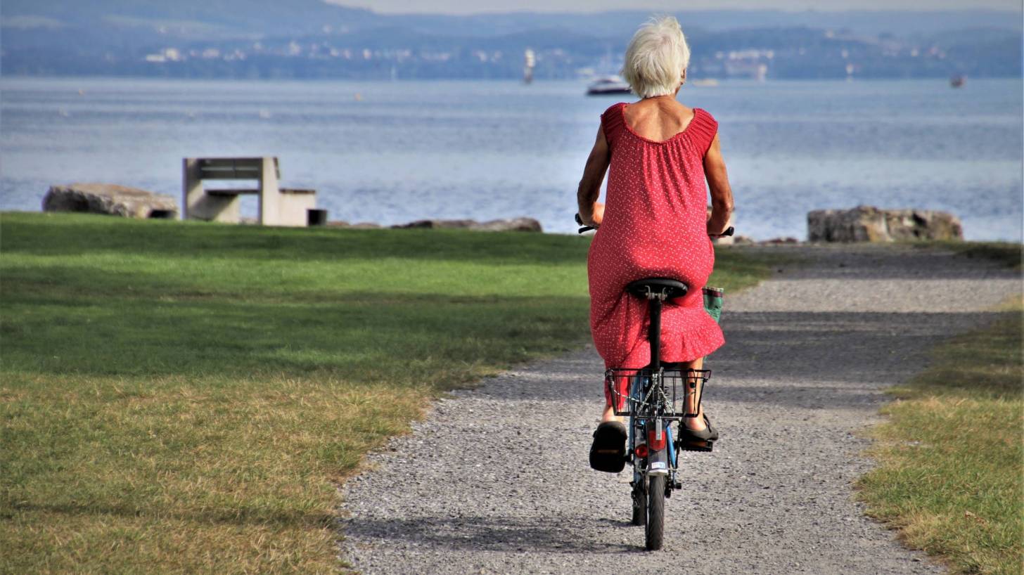 senior woman riding a bike near the ocean