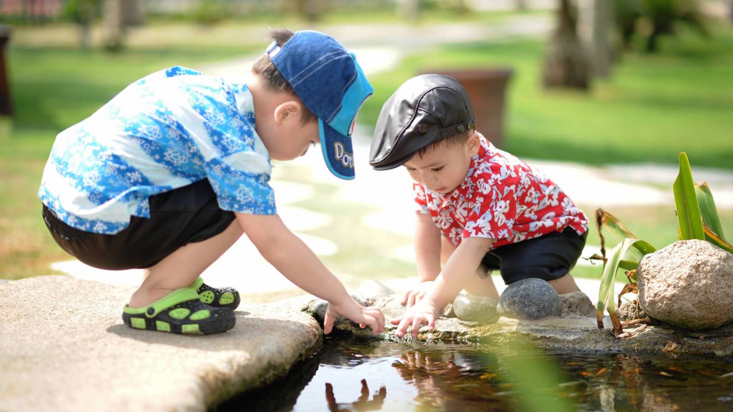 two boys playing in a water pond