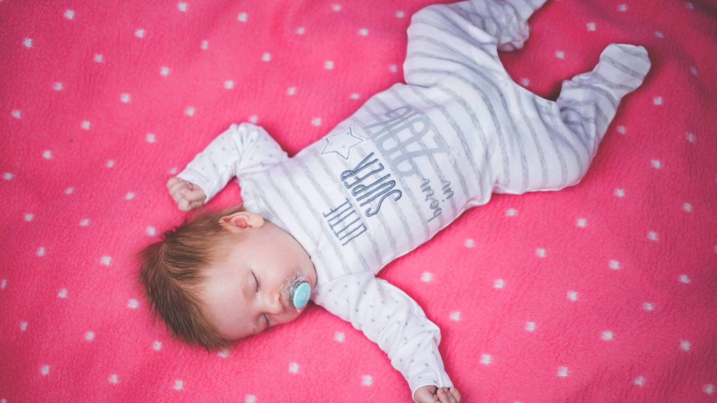 cute infant sleeping on a blanket happy with paci in mouth