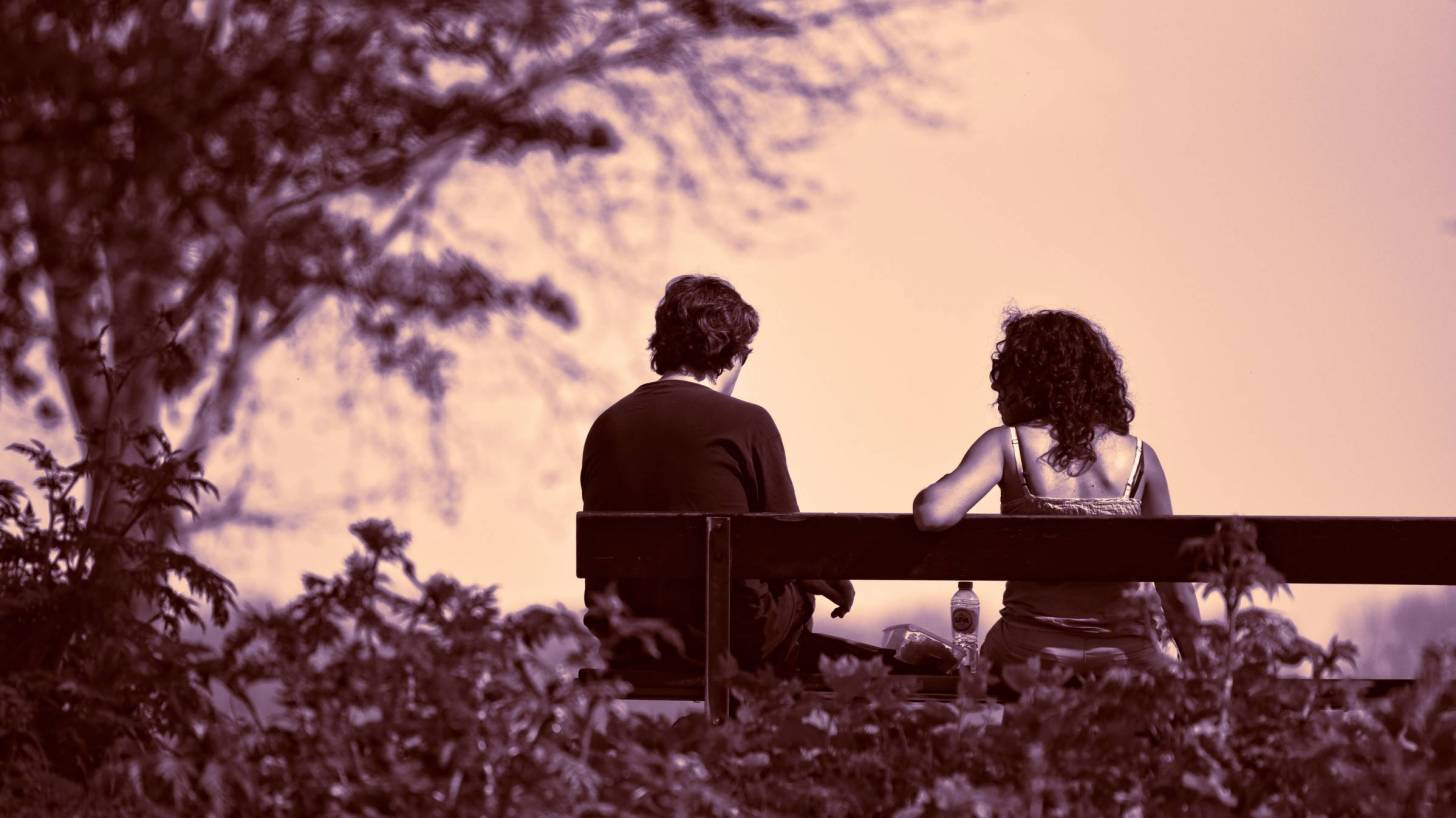 couple sitting on a park bench at dusk