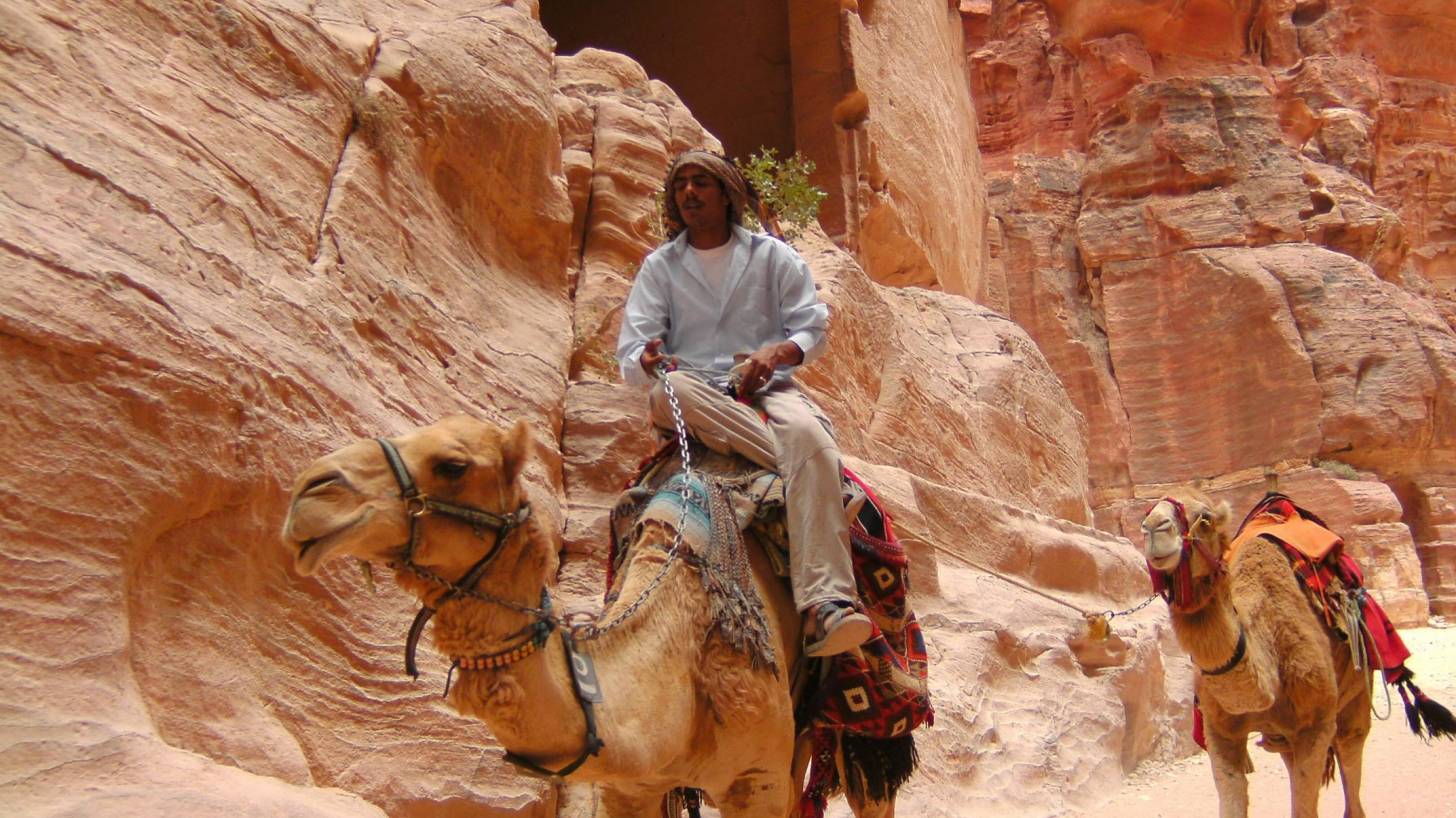 man riding a camel and pulling another behind him