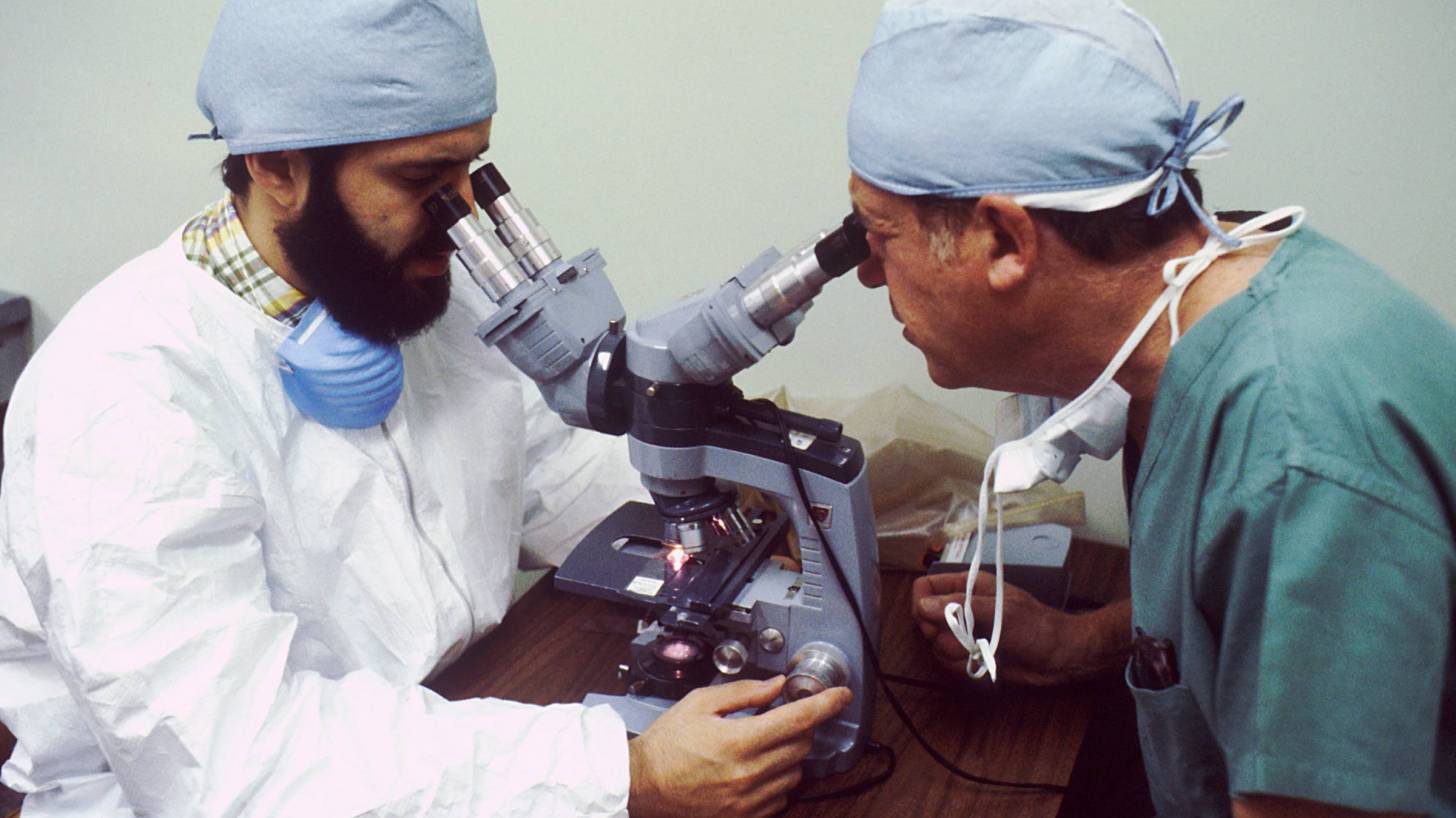 scientists looking through a microscope