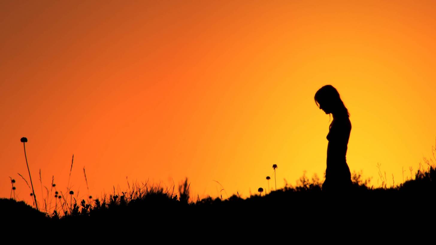 silhouette of lady with sun setting