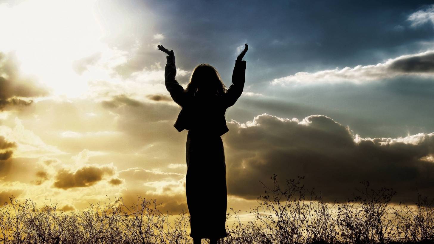 woman raising hands towards the sky in celebration