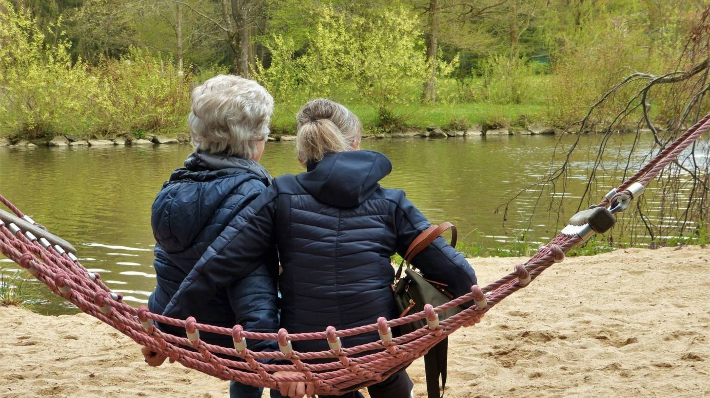 mom and her daughter sitting on a hamock looking at birds on a lake
