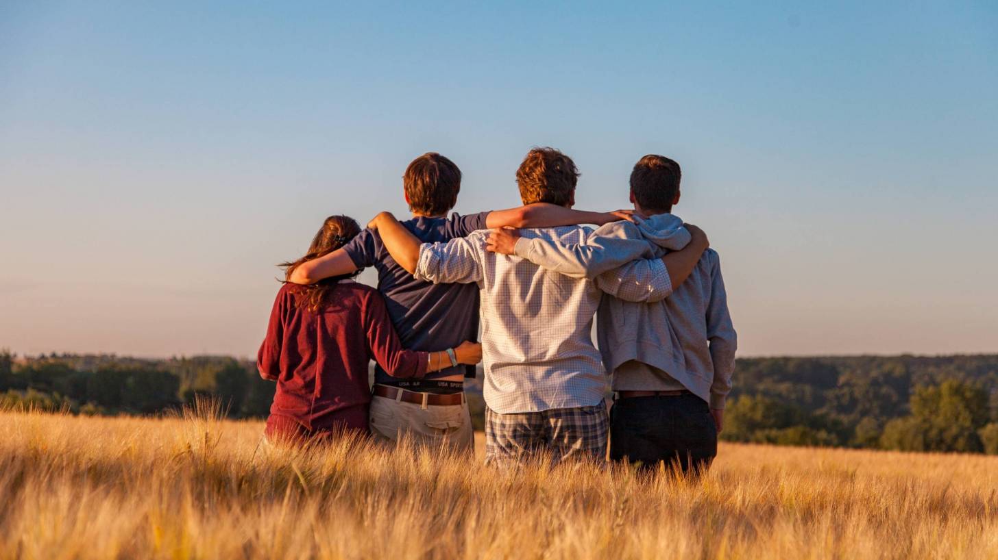 teens holding each other standing in a field