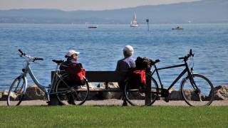 older couple on a bench with their bikes looking at a lake