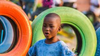 young boy happy standing by colored tires
