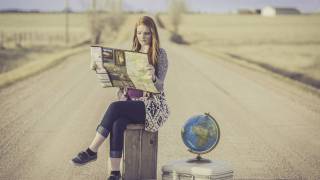 girl on road with globe looking at a map