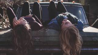 young girls lying on a car chatting