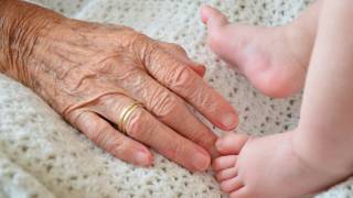 grandma's hand in crib with baby feet, generations