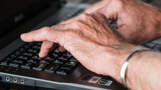 older hands with arthritis typing on a keyboard