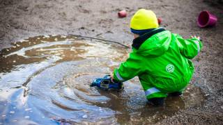 healthy child playing with a truck in a puddle