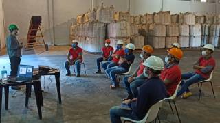 warehouse workers with hard hats on listening to vaccine mandates