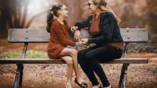 mom and daughter talking on a park bench