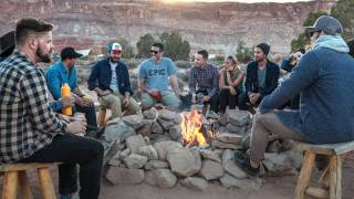 men sitting around an outdoor fire pit