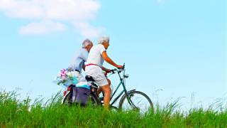 older couple riding a bike under a beautiful sky