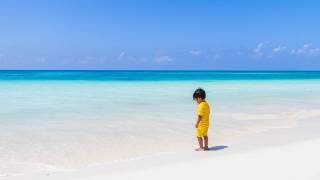 little boy on beach in yellow clothes