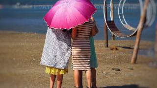 women on a beach protecting from the sun with an umbrella