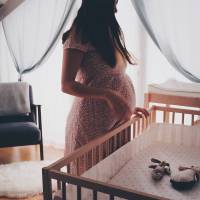 pregnant woman looking at baby crib